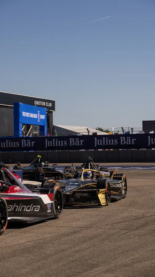 Formula E cars racing through a corner at Berlin Tempelhof