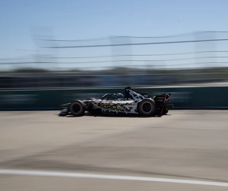 Formula E car with camouflage livery at speed, panning shot, Berlin