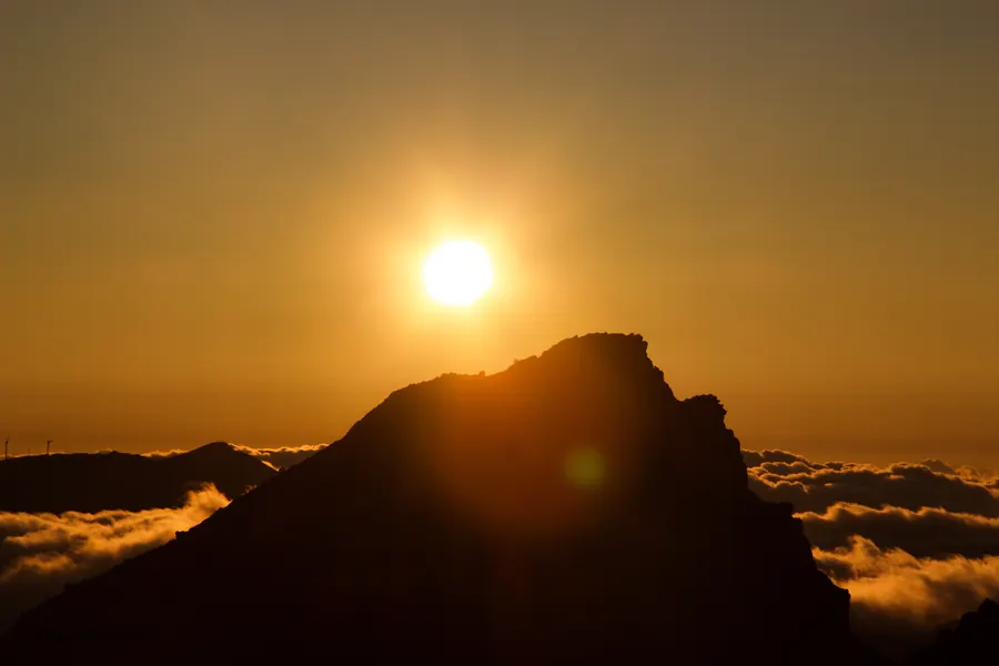Sun setting behind a rock above the clouds, Madeira